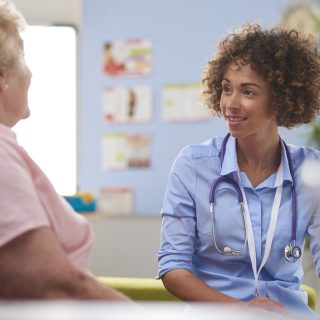 female doctor listening to senior patient